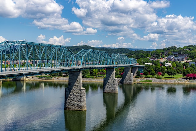 A metal and stone bridge stretches across a river