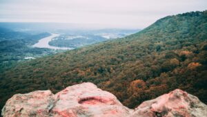 Red rocks in the foreground with a mountain and river valley in the background